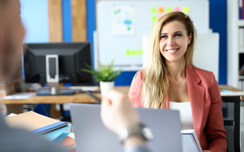 Candidata sorridente durante un colloquio di lavoro con test tecnico e valutazione competenze.